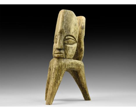 19th century AD. A bone carved statue in the form of a tripod base with tapering legs and two addorsed faces, both with deepl