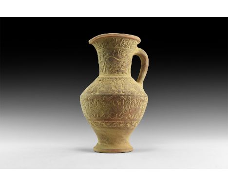 An undated archaistic ceramic pitcher with flared base, biconvex body, flared mouth with pouring lip, strap handle to the rea