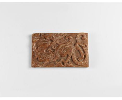 20th century AD. A carved rectangular jade-like stone plaque with high-relief advancing dragon; pierced for suspension.  100 