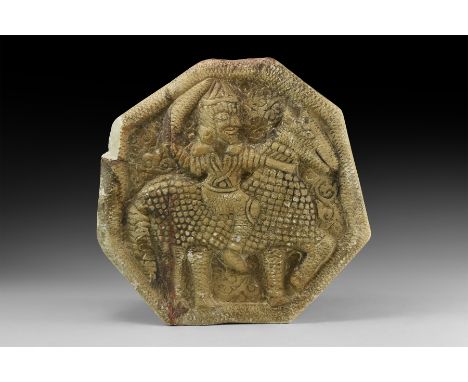 An undated archaistic carved stone irregular octagonal wall tile with raised hatched rim, high-relief horseman with sword dra