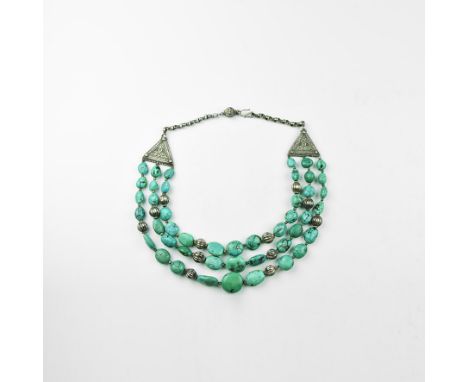 20th century AD. A necklace of graduated irregular turquoise(?) beads in three tiers with base metal melon beads, triangular 