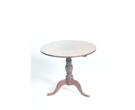 An 18th / 19th Century oak tripod tableThe circular top raised on a ring turned baluster shaft with three down swept supports