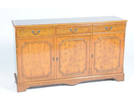 A reproduction yew wood sideboardThe rectangular moulded top above three frieze drawers and three cupboard doors raised on br