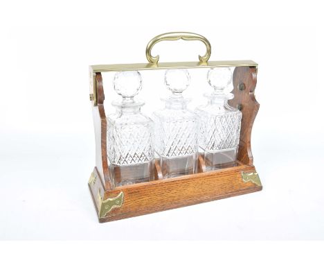 An oak framed and metal mounted three decanter Tantalus, early 20th CenturyHeight 29cm, width 30cm, depth 13cm.