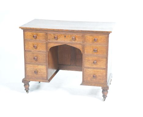 A Victorian kneehole writing deskThe rectangular plank top above an arrangement of nine drawers each with turned wooden butto