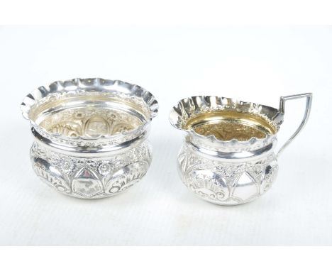An Edwardian silver cream jug and basin, London 1902Of compressed form with an angular handle, the sides embossed with flower