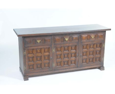 A reproduction oak sideboardWith a rectangular top above three moulded frieze drawers, and three inverted panelled cupboard d