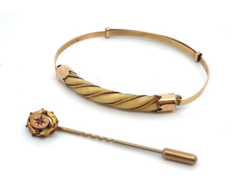 Two jewellery items. An adjustable bangle set with bone in a twisted rope gold surround, stamped 18ct. Together with a ruby s