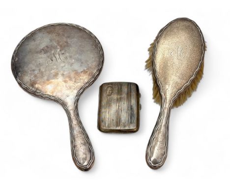 A monogrammed silver backed mirror and dressing table brush, and a cigarette case with engine turned decoration. All with som
