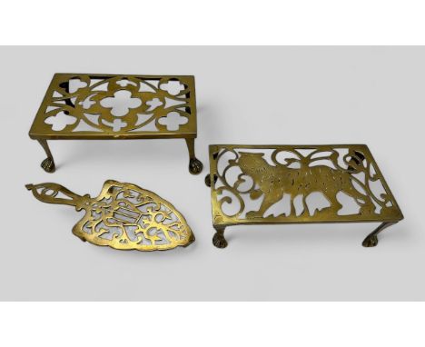 Three vintage /Victorian brass trivets, an iron shaped trivet, a trivet decorated with a tiger, and another with pierced quat