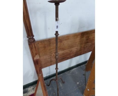 AN IRON FLOOR STANDING CANDLESTICK, THE COLUMN CAST WITH KNOPS AND BALUSTERS ABOVE THE TRIPOD.   H 125cms.