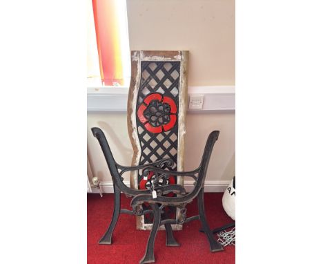 Cast iron garden bench with ornate design, disassembled. Decorative panel with red and black lattice, floral motif. Victorian