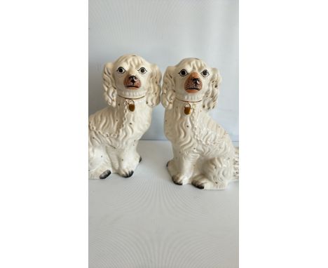 Pair of ceramic dog figurines, white with gold detailing, featuring collars with medallions. Victorian style.