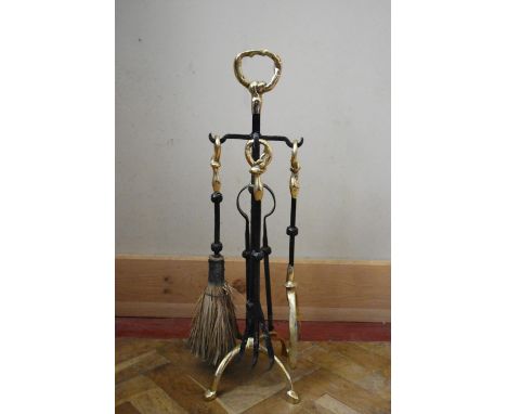A contemporary wrought iron fire stand with four utensils with brass detail to the handles. To include, a fork, shovel, brush