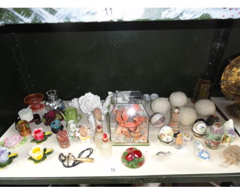 A shelf of assorted items including ceramic flowers, paperweight, scent bottles etc. 