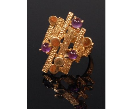 After Andrew Grima - A modern 18ct gold and amethyst set dress ring, of tiered abstract form, with three small cabochon ameth