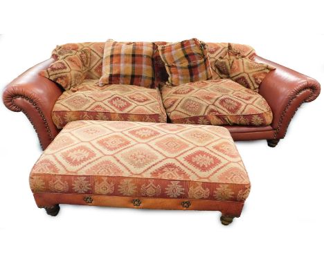 A large red leather four seater sofa, with Persian style patterned cushions on bun feet, and a matching footstool, 252cm W.