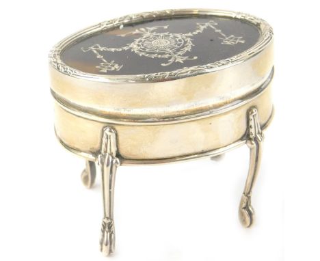 An Edwardian silver, tortoise-shell and pique oval trinket box, the hinged lid enclosing a fitted interior, on tall shaped le