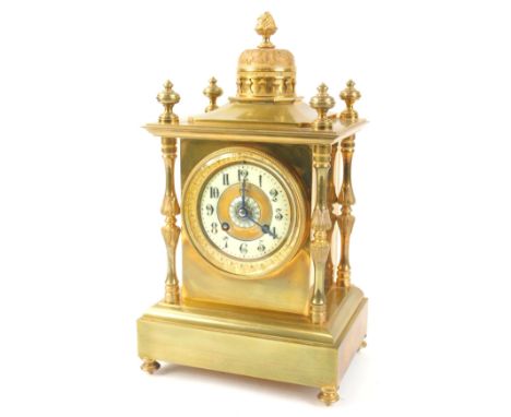A French gilt brass mantel clock, with a central dome, surrounded by turned finials above a cream enamel chapter ring, decora