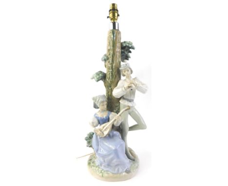 A Nao porcelain lamp base, modelled in the form of musicians beside a tree, 55cm high
