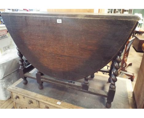 An oval oak gate leg dining table on barley twist legs, top watermarked 3'6 wide 