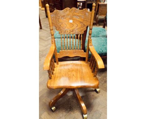 A 1920's light oak sprung frame revolving office elbow chair with bobbin turned panels