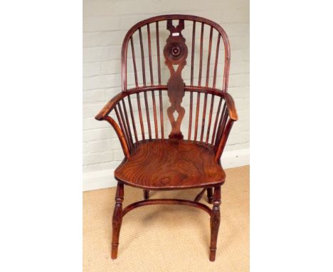 An antique stick back Windsor elbow chair with rosette centre standing on turned legs with hooped cross stretcher 