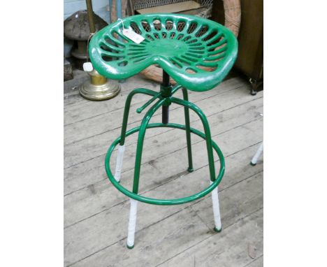 A cast iron adjustable tractor seat on stool base in green 