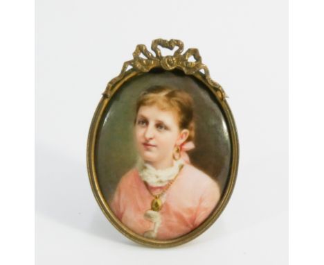 An oval 19th century watercolour miniature portrait on ceramic panel depicting a young girl in a pink dress in a French brass