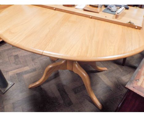 An Ercol light Windsor pattern oval extending dining table with one leaf standing on pillar and quadruple base approx 5' x 3'