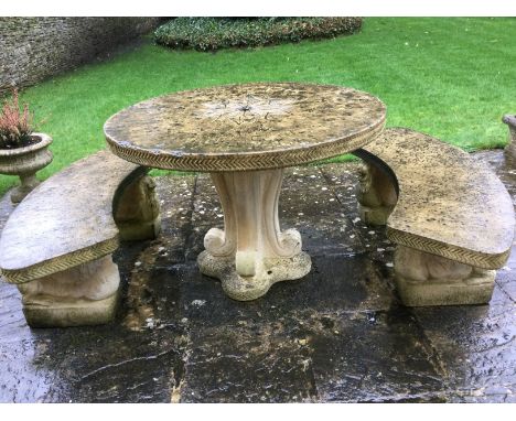 A stoneware circular garden table with two matching concave benches by Stamcombe Stone, Stroud. The table top with central fl