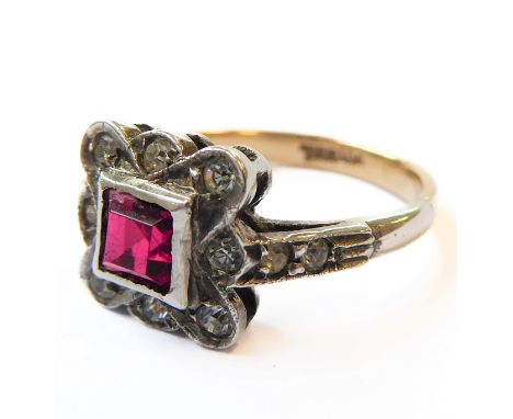 An Art Deco style silver ring with twelve small diamonds surrounding a central square cut stone (possibly ruby), ring size K