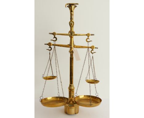 A set of continental two-pan brass merchant's scales; the finial cast as a bull's head above a turned stem and shaped base wi