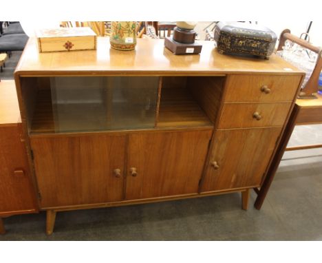 A teak sideboard, fitted display shelf enclosed by glazed sliding doors, cupboards and two short drawers below, raised on sle