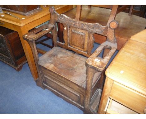 A SMALL OAK MONKS BENCH, the lift up seat flanked by stick compartments