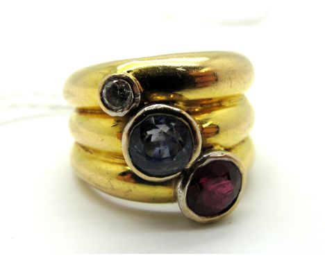 A Wide Three Row Style Ring, graduated circular collet offset with a ruby, sapphire and a brilliant cut diamond, indistinctly