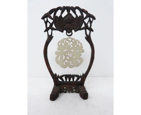 A mid 20th century carved celadon jade pendant on a carved wooden stand. A pale celadon jade pendant in the form of the Chine