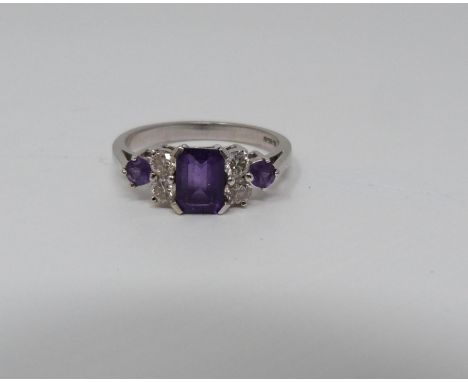 An Amethyst and diamond 18ct white gold ring, set to centre with a emerald cut amethyst in a four claw setting with an approx