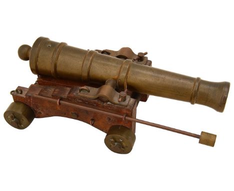 An early 20th century bronze table top model signalling cannonthe ringed barrel mounted on stepped oak carriage on bronze whe