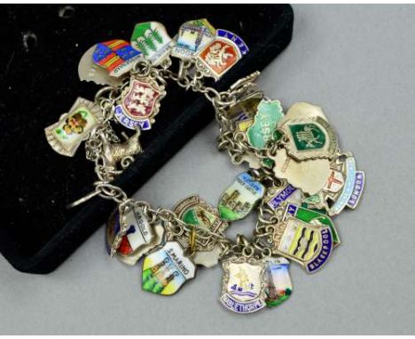 A CHARM BRACELET, the belcher link chain suspending mainly enamel town charms, to include London, Jersey, Berlin and Birmingh