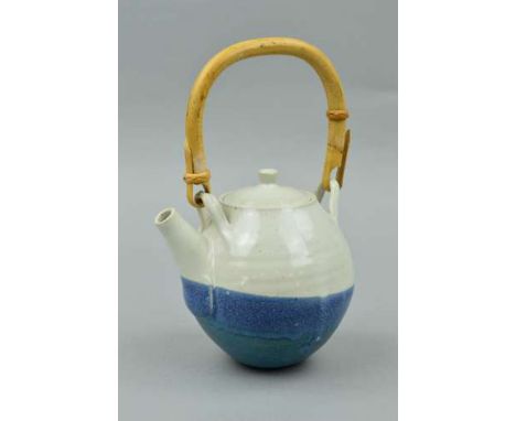 A TEAPOT IN THE STYLE OF DAVID LEACH, the spherical body is decorated with a blue and white glaze and has a cane handle, unma