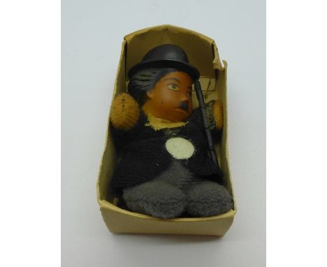 A vintage Charlie Chaplin miniature doll and a Kewpie charm