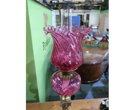 Early 20th C oil lamp on brass corinthian capped column and stepped base, cranberry glass reservoir and shade with clear glas
