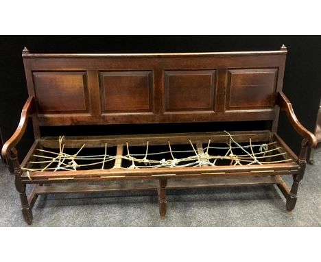 An 18th century oak settle, four fielded panel back, open arms, turned and blocked forelegs. 104cm high x 188cm wide x 69cm d