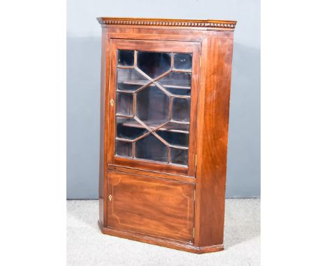 A George III Corner Cupboard with moulded cornice and dentil frieze, fitted two shelves enclosed by a single astragal glazed 