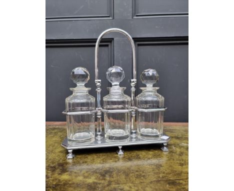 An electroplated three bottle decanter stand,&nbsp;by Lee and Wigfull,&nbsp;34cm high, (the set of three decanters and stoppe