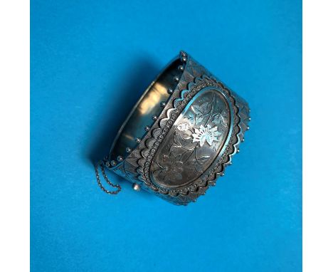 A Victorian silver hinged bangle with beaded border and chased relief floral panel, Chester 1882 