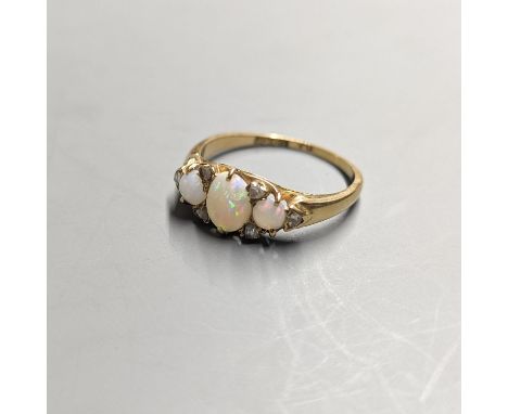 An early 20th century 18ct and  three stone white opal set ring, with diamond chip spacers, size Q/R, gross 3.7 grams.