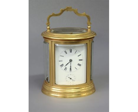 FRENCH GILT METAL OVAL CARRIAGE CLOCK late 19th century, the enamelled dial with Roman numerals above a subsidiary alarm dial