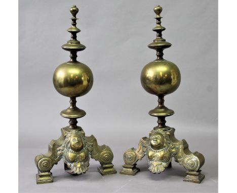 PAIR OF DUTCH STYLE BRASS FIRE DOGS the orb body between a disc knopped finial and stem and mask base, height 62cm (2)
